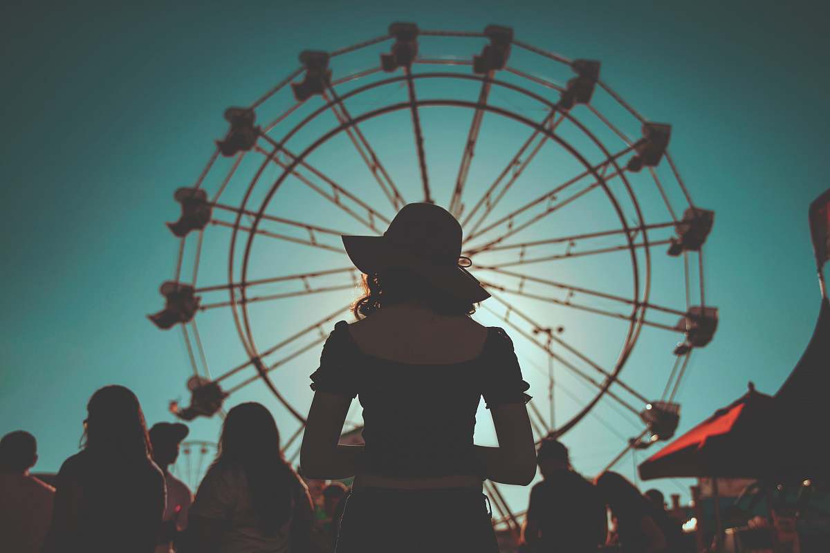 ferris wheel woman standing in front of ferris wheels surrounded with people amusement park